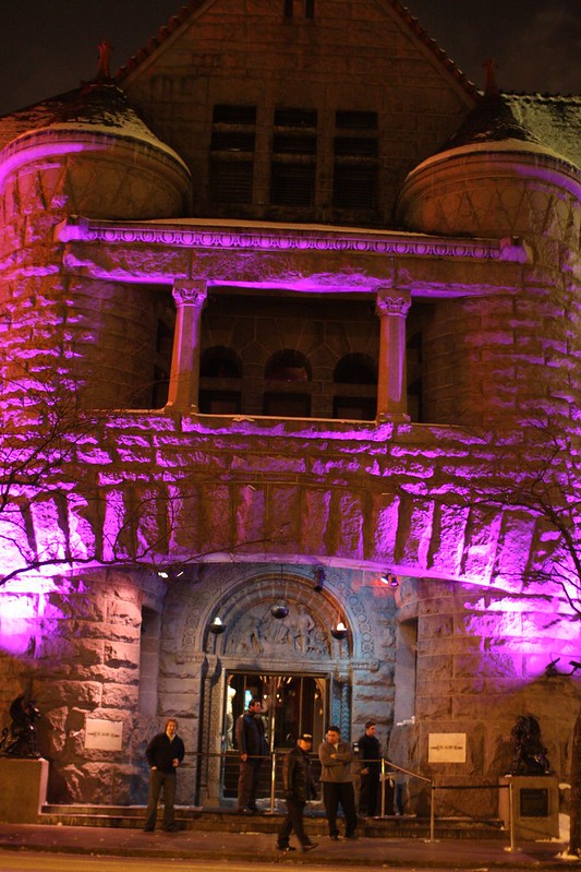 Facade of the Excalibur at night lit with purple lights, with a small crowd at the entrance. 